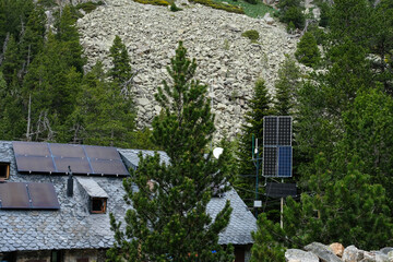 Installation of solar panels on the roof of a mountain house. Mountains background with coniferous...
