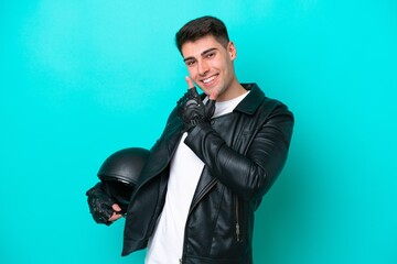 Naklejka premium Young caucasian man with a motorcycle helmet isolated on blue background happy and smiling