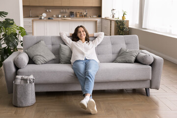 Peaceful young lady relaxing on comfortable couch at modern flat