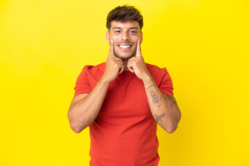 Young caucasian handsome man isolated on yellow background smiling with a happy and pleasant...