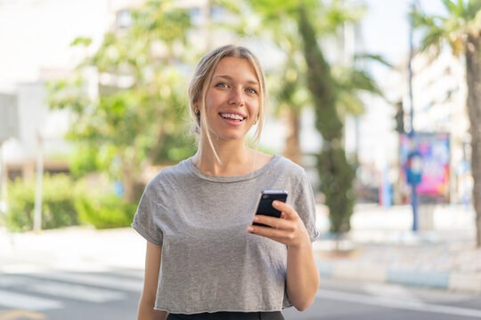 Young blonde woman at outdoors using mobile phone