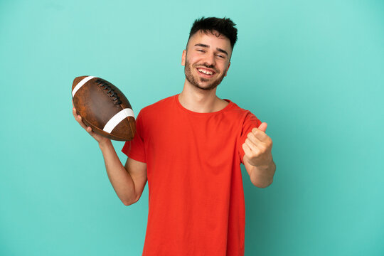 Young Caucasian man playing rugby isolated on blue background making money gesture