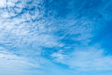 Obraz premium Clear blue sky with soft scattered clouds, perfect for use as a natural background in design, web, advertising, presentations, and minimal concept layouts or sky texture overlays.