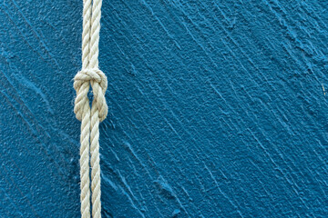 Tied rope knot on textured blue background, symbolizing strength, teamwork, trust, and connection. Perfect for business, maritime, or communication concepts in visual design.