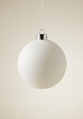 Minimalist white Christmas bauble hanging on a neutral background. Vertical photo of a simple holiday ornament with a matte finish. Festive decoration with copy space