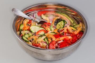 Vegetable salad in large stainless steel kitchen bowl with spoon