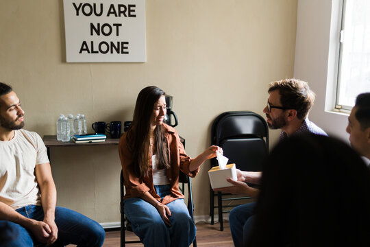 Woman crying getting tissue during group therapy session - Powered by Adobe