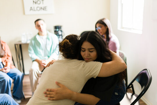 Woman receiving hug in support group meeting