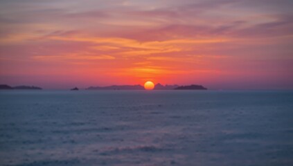 Fototapeta premium Vibrant sunset paints the sky with fiery oranges and soft pinks over a calm ocean horizon, evoking tranquility and natural beauty.