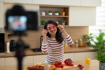Woman vlogging and playing with bell pepper in kitchen
