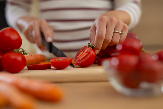 Woman preparing healthy meal slicing fresh tomatoes - Powered by Adobe