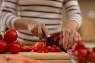 Woman cutting fresh tomatoes on wooden board