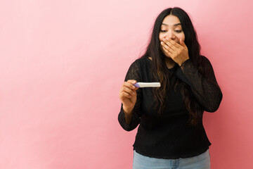 Excited woman getting surprised at positive pregnancy test result