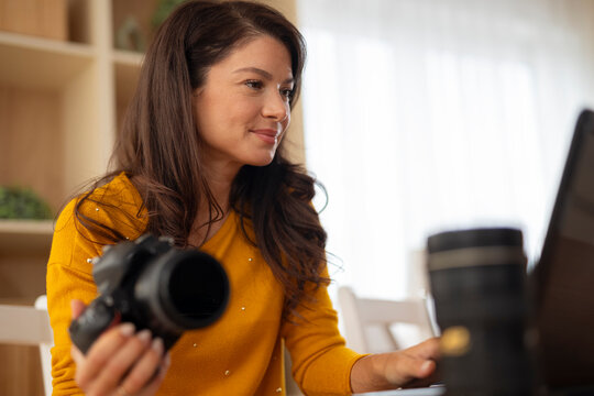 Woman photographer editing images on laptop at home