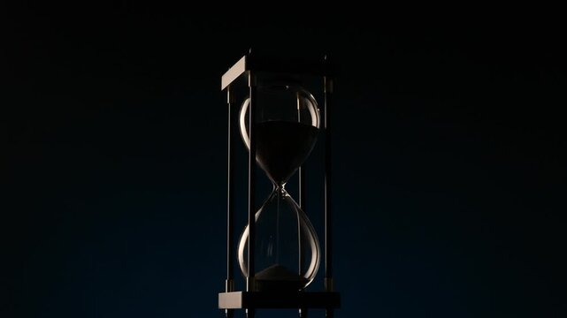 black sand hourglass rotating gracefully on a dark background � concept of renewal, time, and inner stillness within motion.