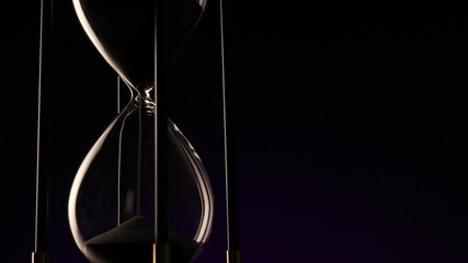 dark hourglass with fine sand flowing, a metaphor for the irreversible passage of time and life�s fragile continuity. - Powered by Adobe