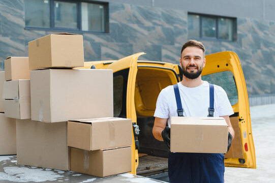 Courier holding cardboard box next to delivery van full of packages