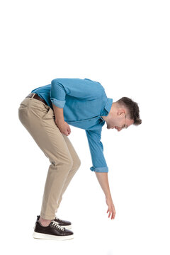 Happy casual man bending over and reaching down