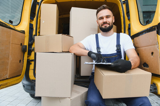Deliveryman checking packages in van with clipboard