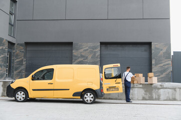 Delivery driver loading cardboard boxes into yellow van