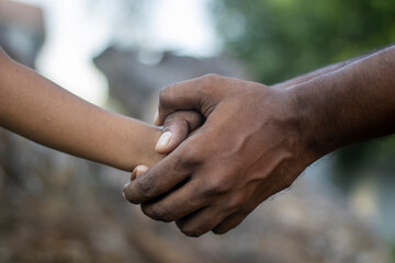 Adult hand holding a childs hand, symbolizing care and connection