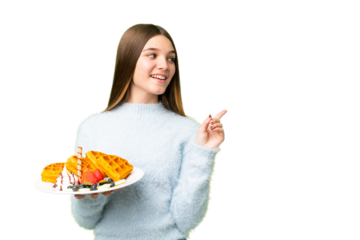 Teenager girl holding waffles over isolated chroma key background intending to realizes the solution while lifting a finger up