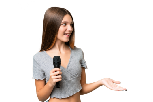 Teenager singer girl picking up a microphone over isolated background with surprise expression while looking side