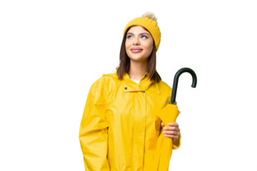 Young Russian woman with rainproof coat and umbrella over isolated chroma key background thinking an idea while looking up