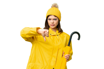 Young Russian woman with rainproof coat and umbrella over isolated chroma key background showing thumb down with negative expression