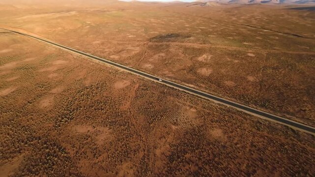 Aerial view of a lonely car driving on a desert highway