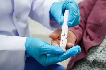 Asian senior woman using lancet pen on senior patient finger for check sample blood sugar level to treatment diabetes.