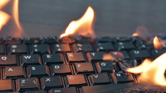 Burning keyboard. Keyboard is engulfed in flames on a desk.Close up of a burning keyboard on fire.