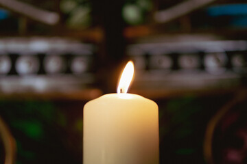 Single burning candle in church — warm soft flame symbolizing prayer, faith, remembrance and peace in spiritual atmosphere