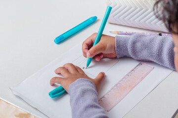 A little Asian girl learning to draw using a pen on a table