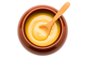 Ceramic pot of smooth yellow mustard with a wooden spoon isolated on transparent background