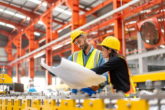 engineer worker man woman in safety vest and helmet check material with blueprint, people working in industrial manufacturing factory planning to inspect repairing equipment in production warehouse