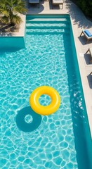 A vibrant yellow inflatable ring floats peacefully atop a crystal-clear turquoise swimming pool, inviting a refreshing dip on a bright, sunny day.