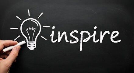 A hand drawing a light bulb and the word inspire on a chalkboard with chalk