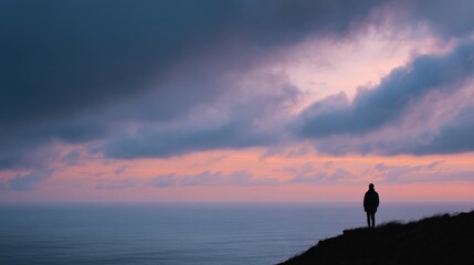 Silhouette Of Person Standing On Cliff At Sunset Over Ocean. Contemplation And Solitude In Nature