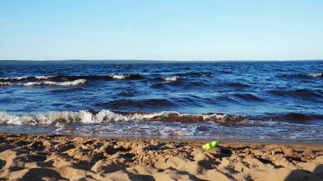 Waves gently crash on shore of sandy beach at Lake Onego in Karelia. Scene captures beauty of nature and tranquility of water during sunset. Dark water with high iron content, sand containing shungite
