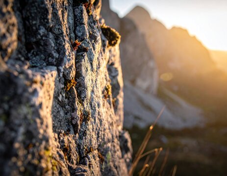 Close-up of rough rock face with sunlight backlighting distant mountains