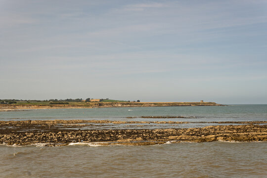 A beach with a rocky shoreline and a small town in the distance