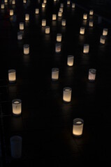 Many small paper lanterns lit up in a dark room with a warm glow and soft shadows on the floor.