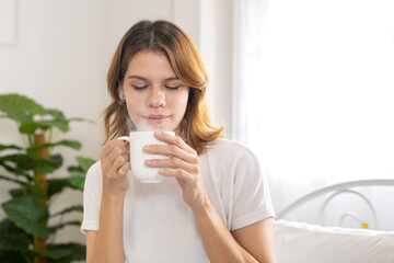 women enjoying hot drink in morning at home. Relaxed moment of mindfulness and comfort, cozy lifestyle with warm beverage in bright, natural light bedroom.