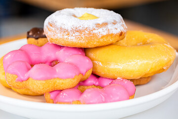 Close-up of sugar-coated donuts on white plate. Studio shot, unhealthy food