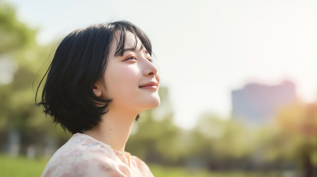 晴れた日の公園で柔らかな笑顔で空を見上げる美しい女性
