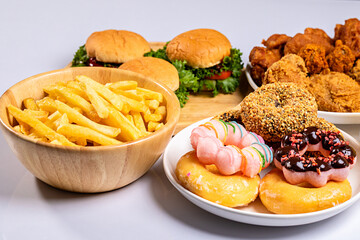 French fries, burgers and other fast food on wooden table against white background