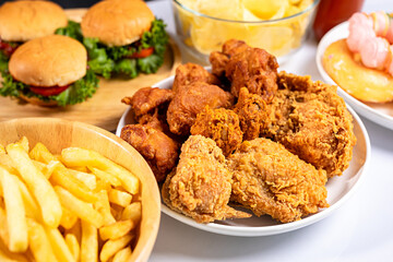 Close-up of unhealthy fast food, hamburger, fried chicken, donuts and french fries on plate.