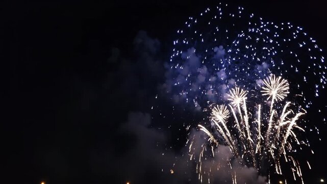 Brilliant blue and white fireworks exploding in the night sky. Festive pyrotechnic display for a holiday celebration