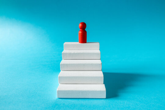 Achieving success. Stages of development. The leader of the organization at the top. White stairs leading up. The path to achieving the goal. Business concept. close up. copy space. Blue background
